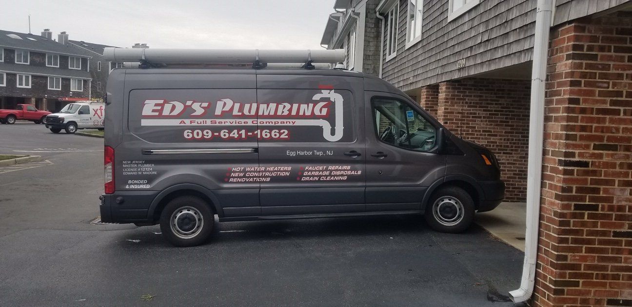 A ed 's plumbing van is parked in front of a brick building.