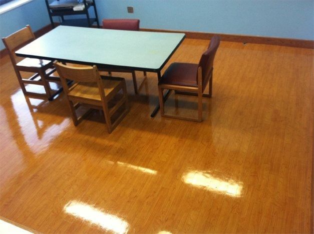 Table and three chairs in room with shiny wooden floor.