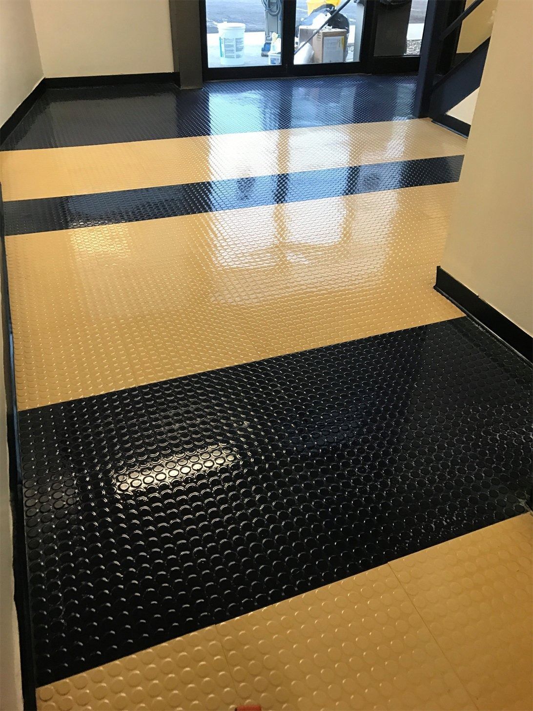 Black and beige patterned floor, leading to a glass door.
