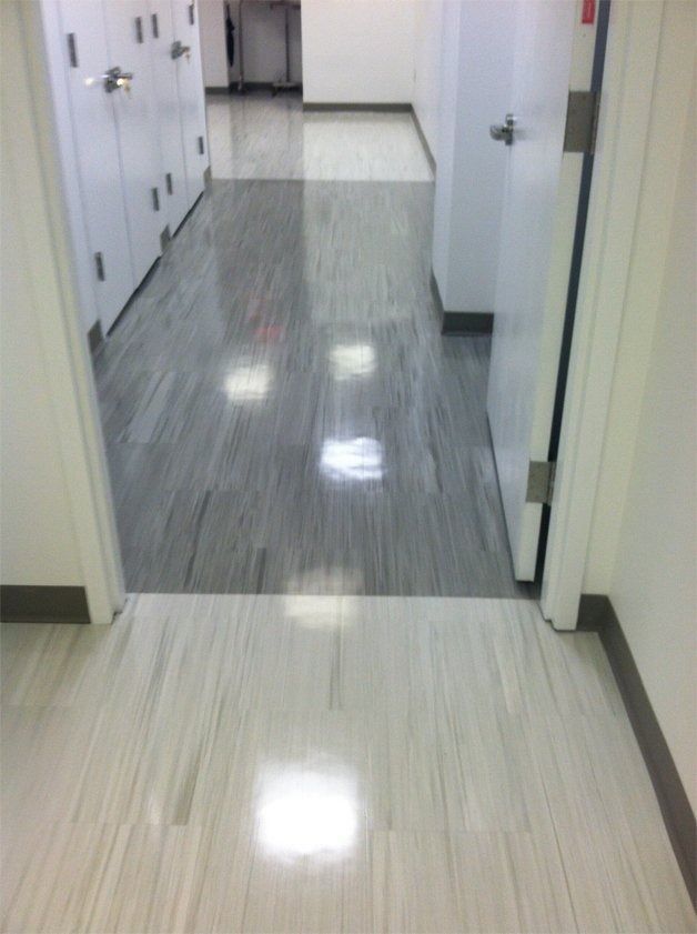 Hallway with light-colored flooring, leading to a darker gray area. White doors and cabinets line the walls.