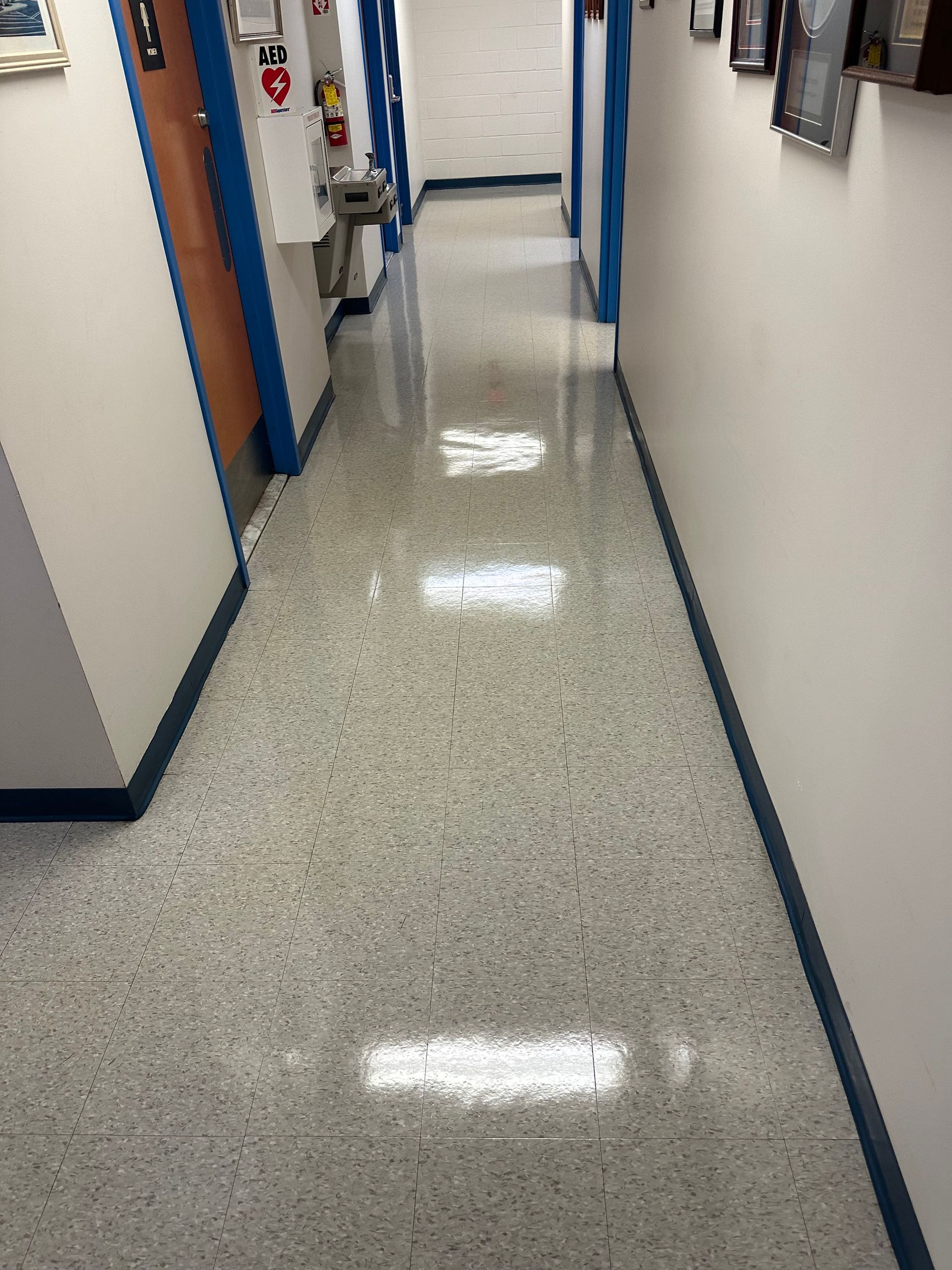 Long hallway with gray speckled floor, white walls, and blue trim.