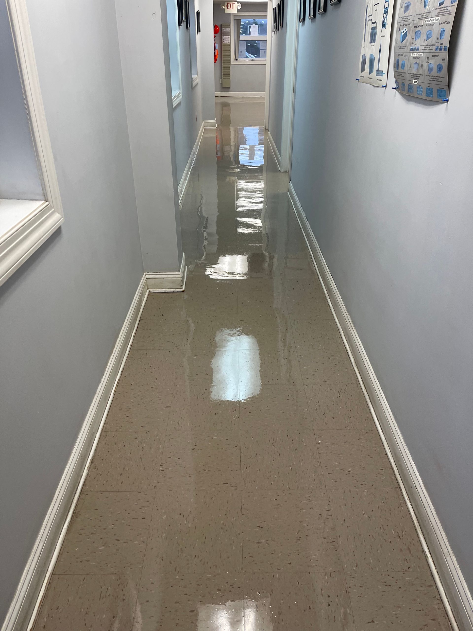 A narrow, glossy hallway with light-colored flooring and gray walls.