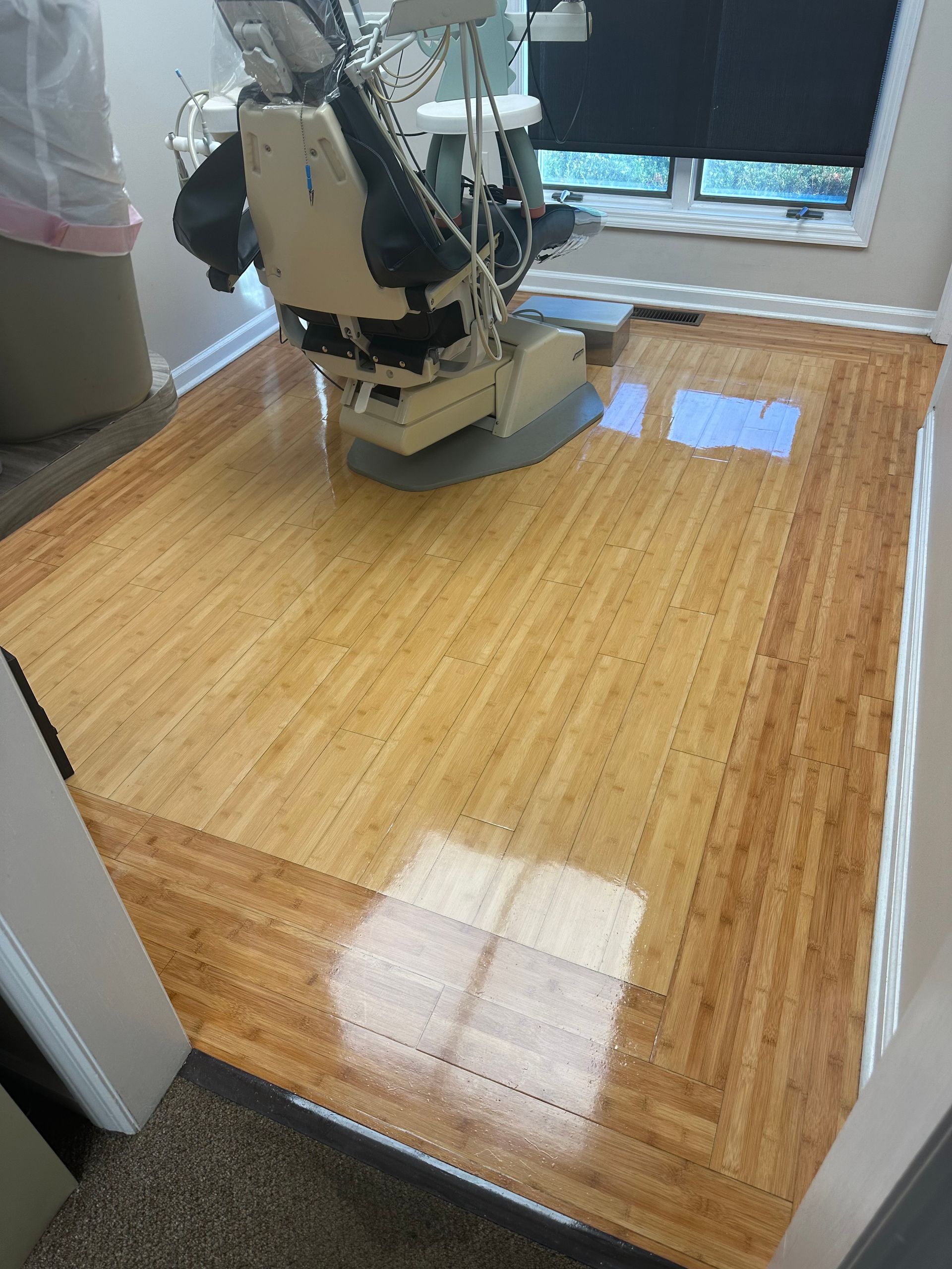 Floor being refinished with sanding machine; shiny, light wood with a dark border.