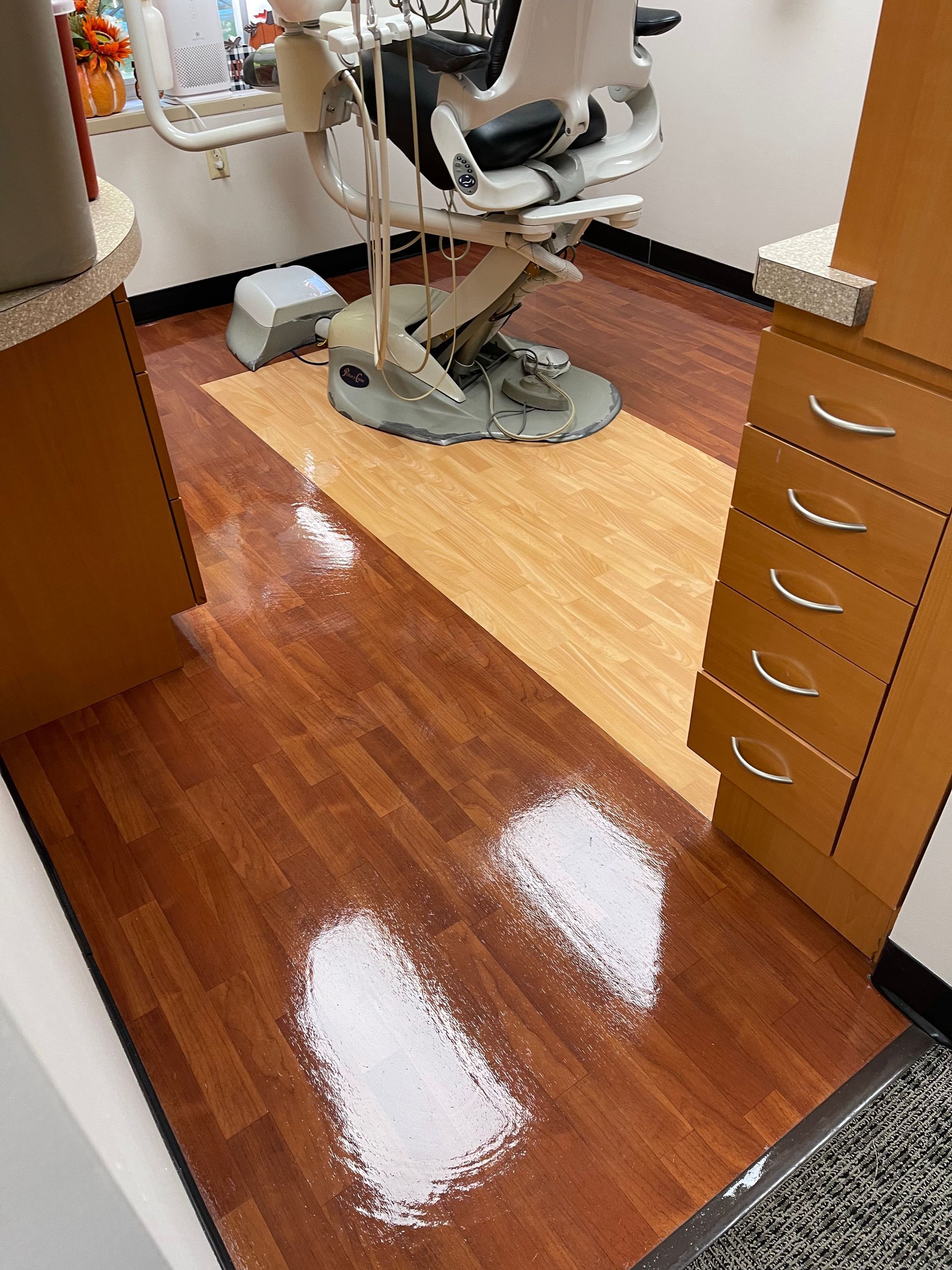 A dental operatory room with a chair, cabinets, and a spill of white powder on the wooden floor.