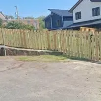 Wooden fence in front of a house, with a blue sky overhead.