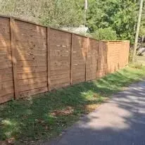 Wooden fence along a grassy area next to a road.