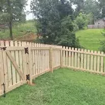 Wooden picket fence surrounding a grassy backyard.