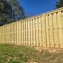 Wooden fence on a grassy hill against a clear blue sky.