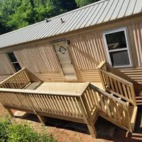 Wooden deck and ramp leading to a mobile home with metal siding and a window.