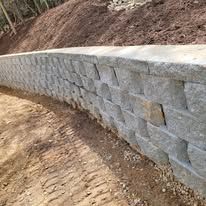 Gray stone retaining wall curving along a hillside.
