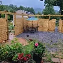 Outdoor dining area with a wooden fence, picnic table, and colorful flowers.