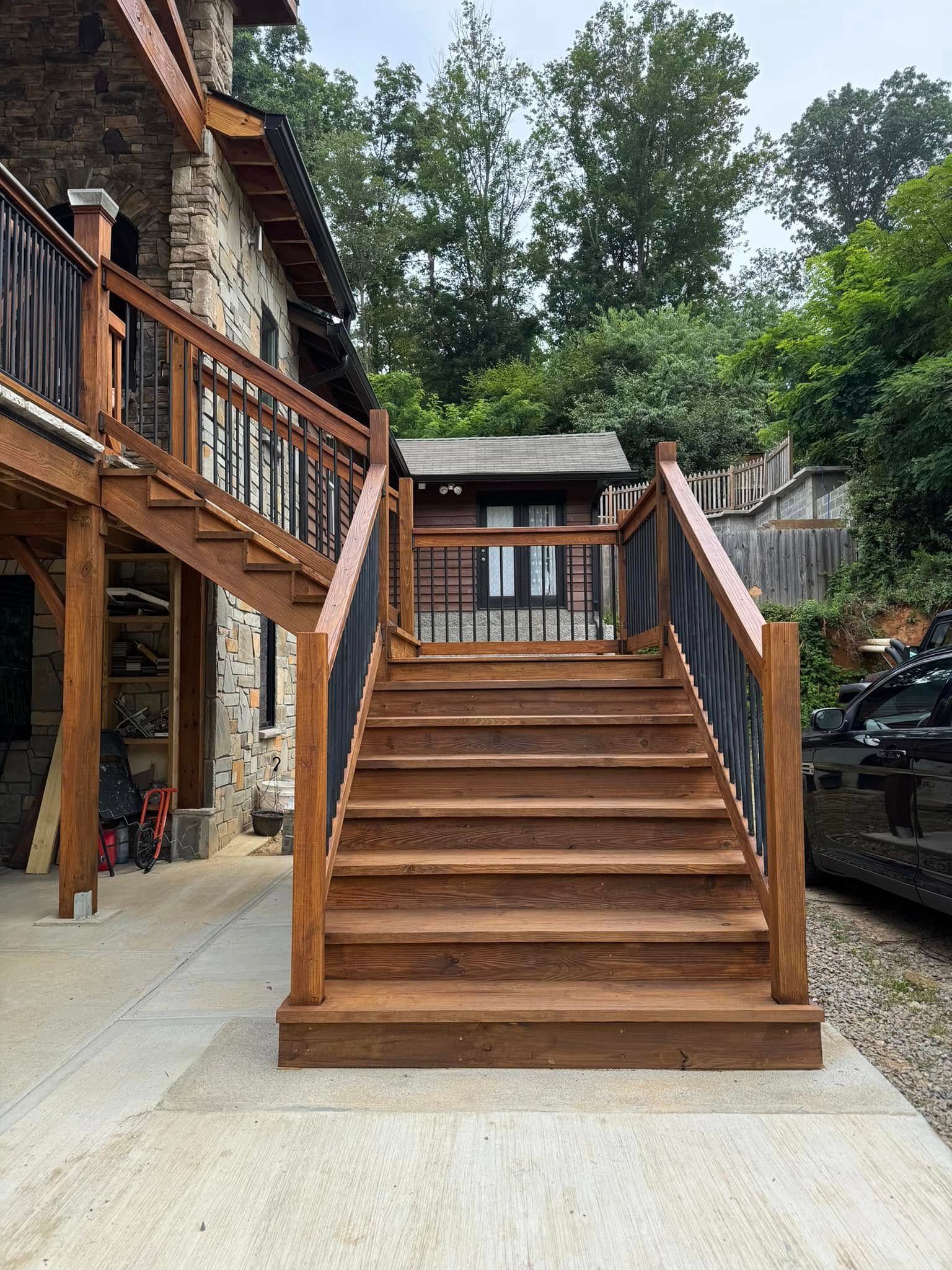 Wooden outdoor stairs leading up to a structure, set next to a stone house.