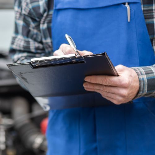 Person in blue apron writing on a clipboard, likely checking inventory or taking notes.
