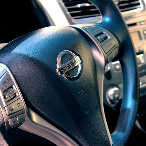 Close-up of a Nissan steering wheel and dashboard controls inside a car