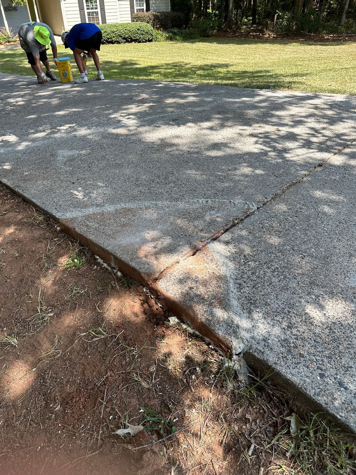 Two men are working on a concrete driveway.
