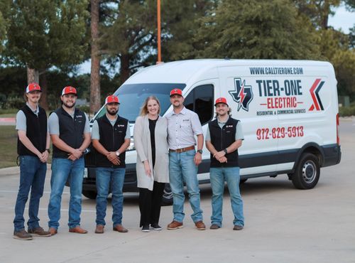 Six people are posing beside a white TER-DOE Electric van outdoors in a parking lot.