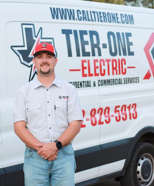 Man standing beside the Tier-One Electric van, wearing a cap, white shirt, and jeans.