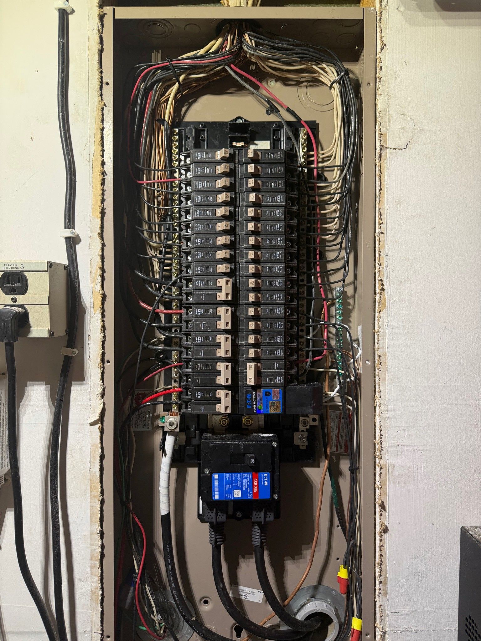 Open electrical breaker panel with exposed wiring and a blue digital meter display.