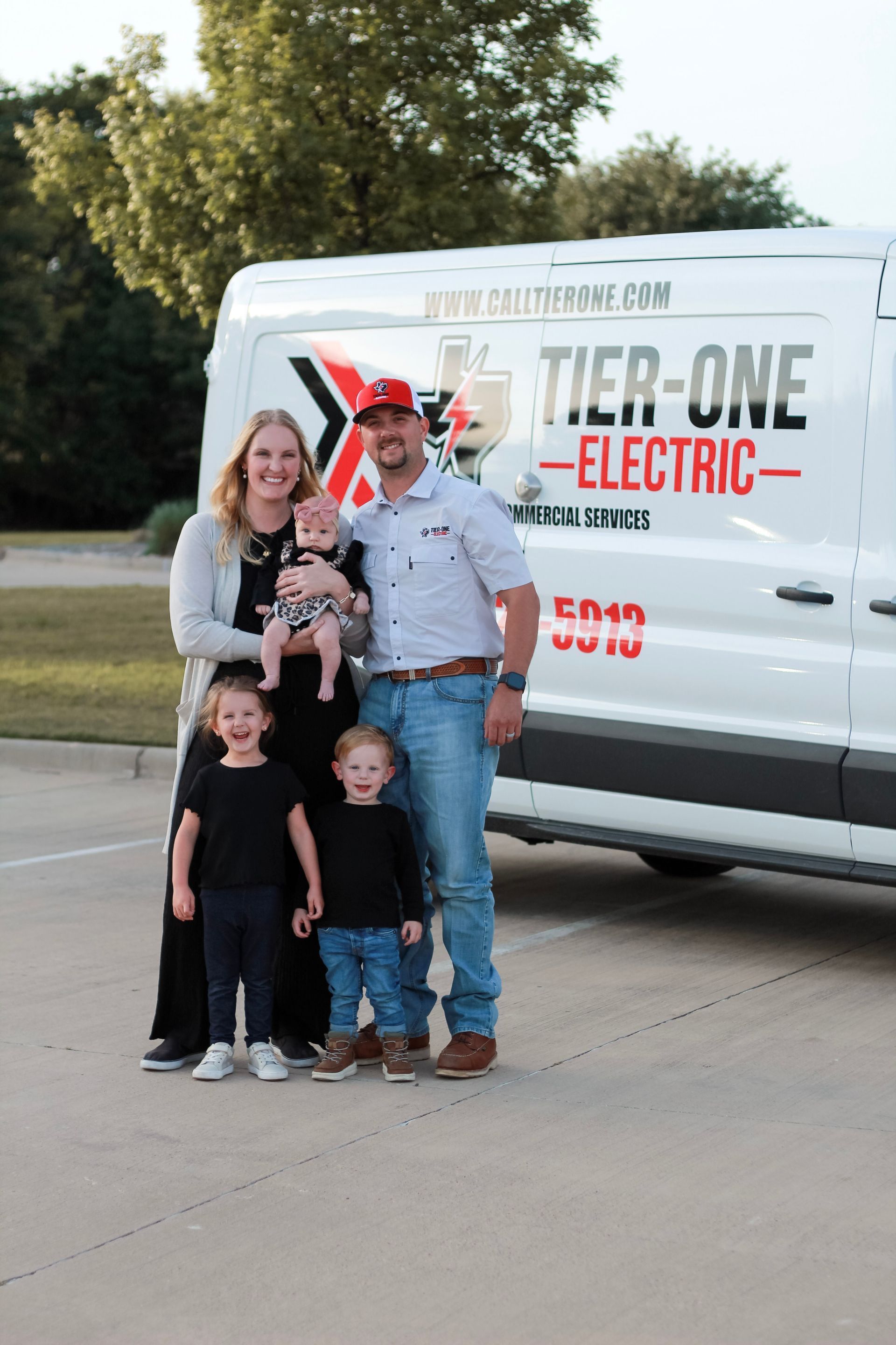 Family posing in front of a white Tier One Electric service van