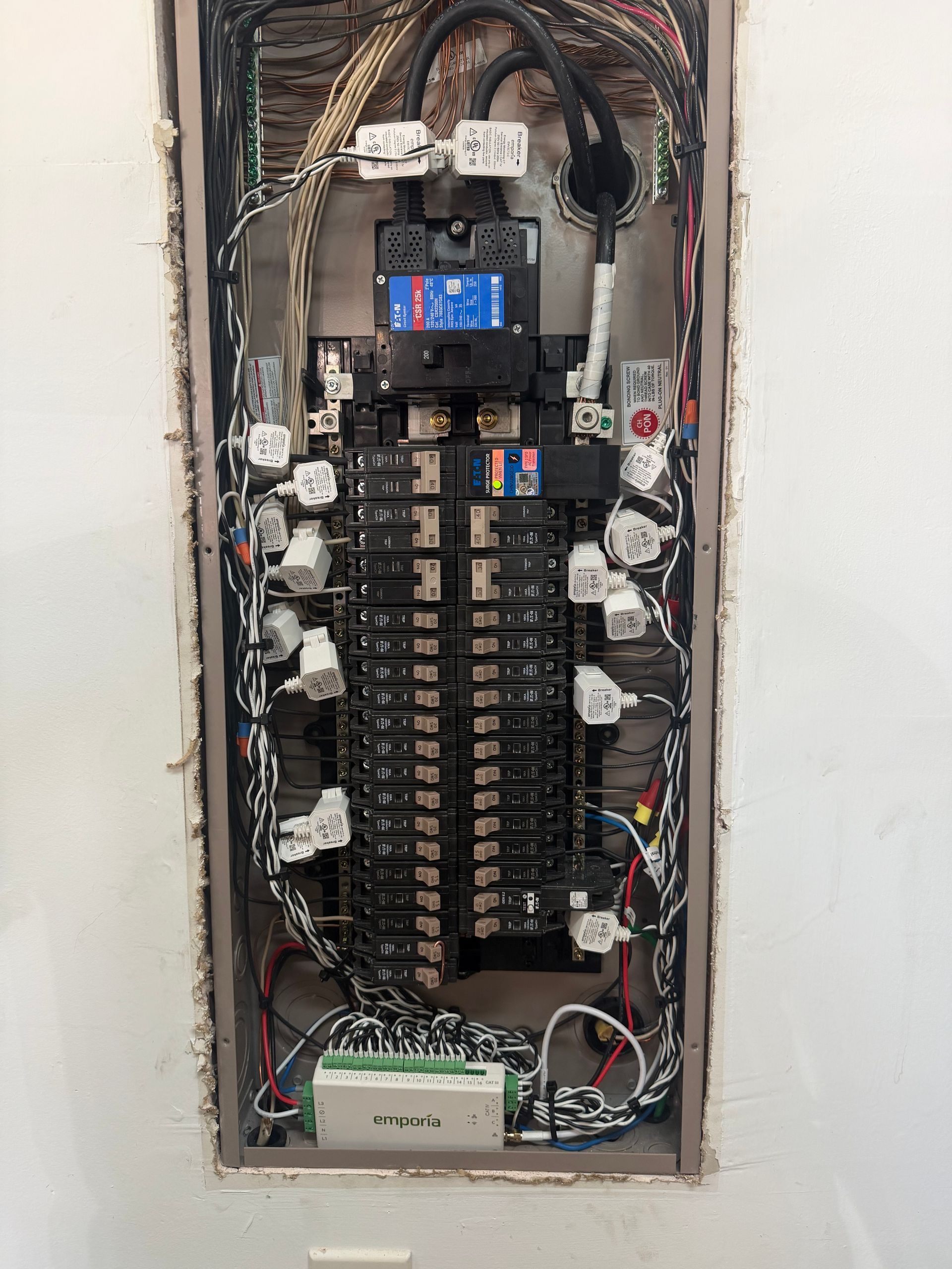 Open electrical breaker panel with exposed wiring, switches, and circuit breakers.