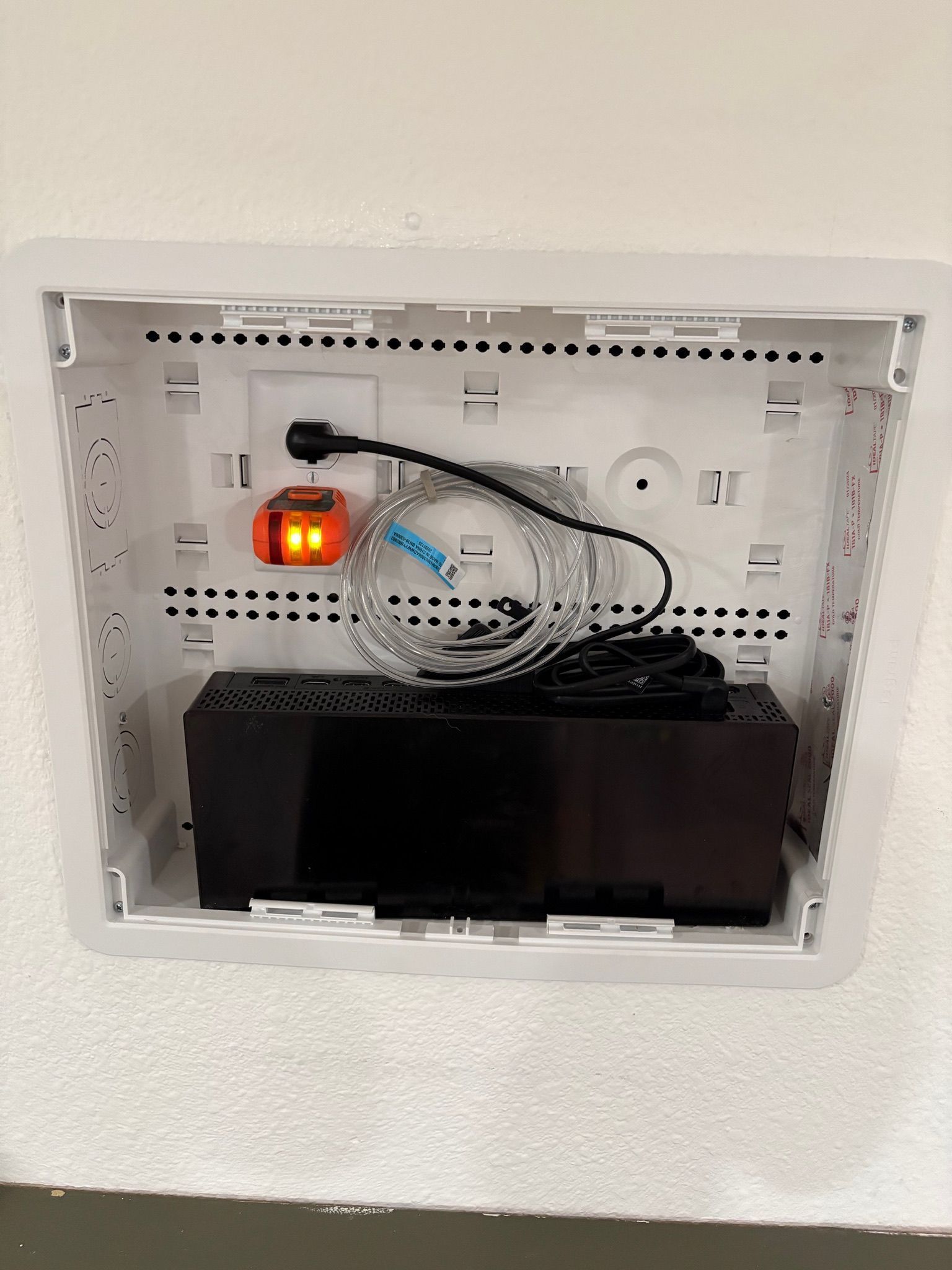 Open wall niche with router, cables, and a black device inside a white frame