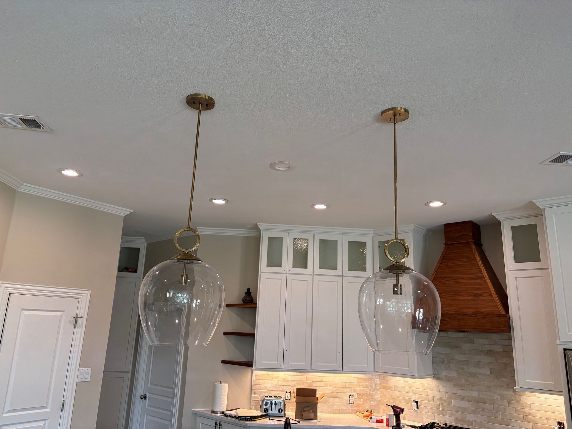 Modern kitchen with white cabinets, pendant lights, and a copper range hood above the stove