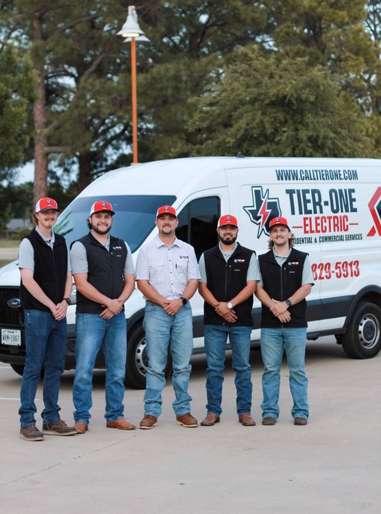 Five workers in caps and vests stand in front of a Tier-One Electric service van.