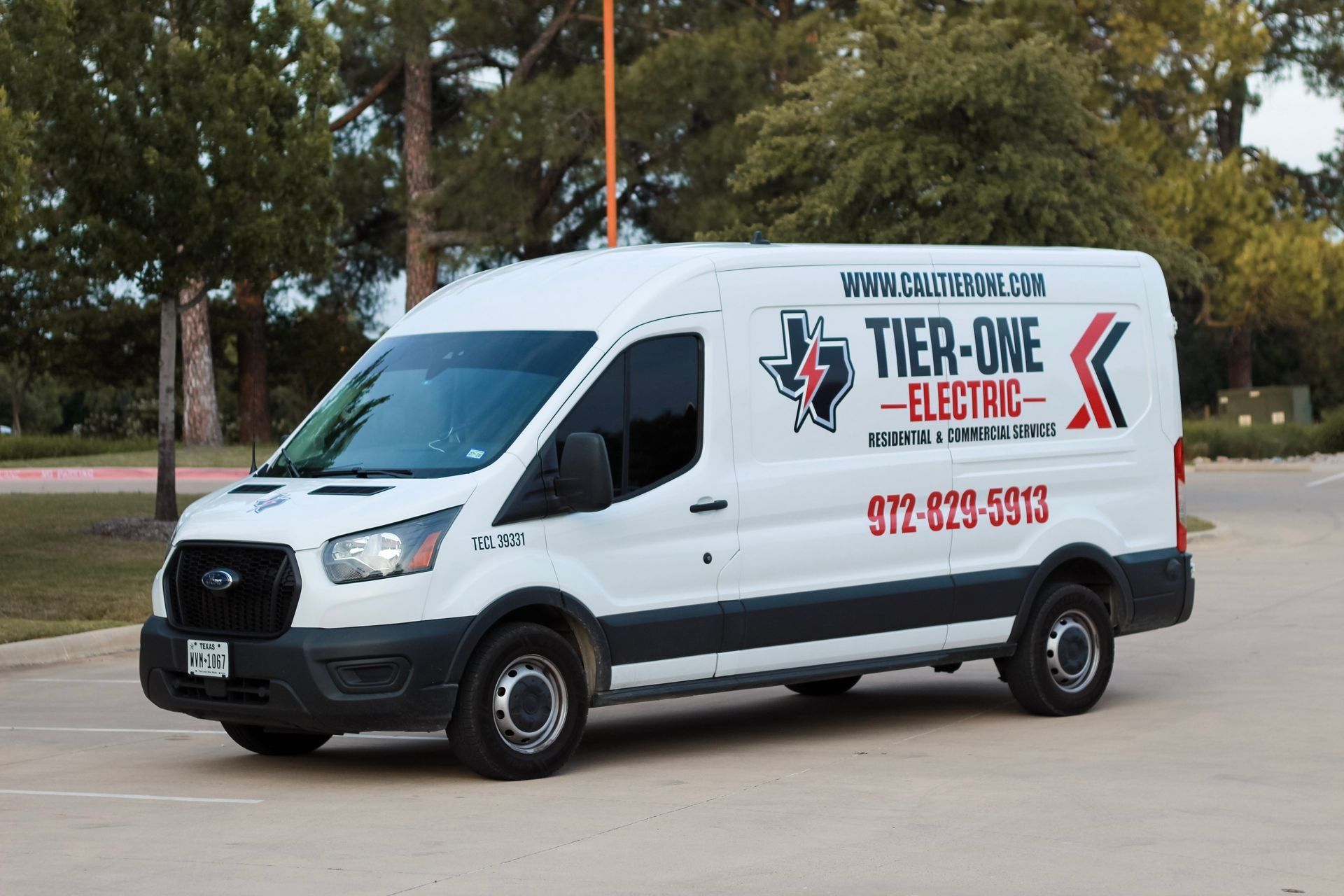 White Tier-One Electric service van parked on a street, with logo and phone number on the side