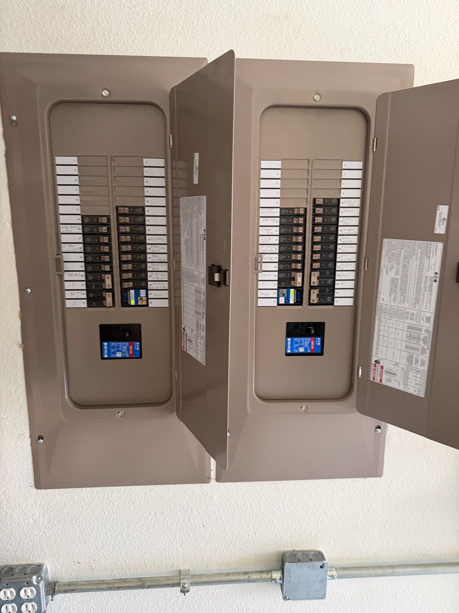 Two residential electrical panels with labeled circuit breakers installed by Tier-One Electric.