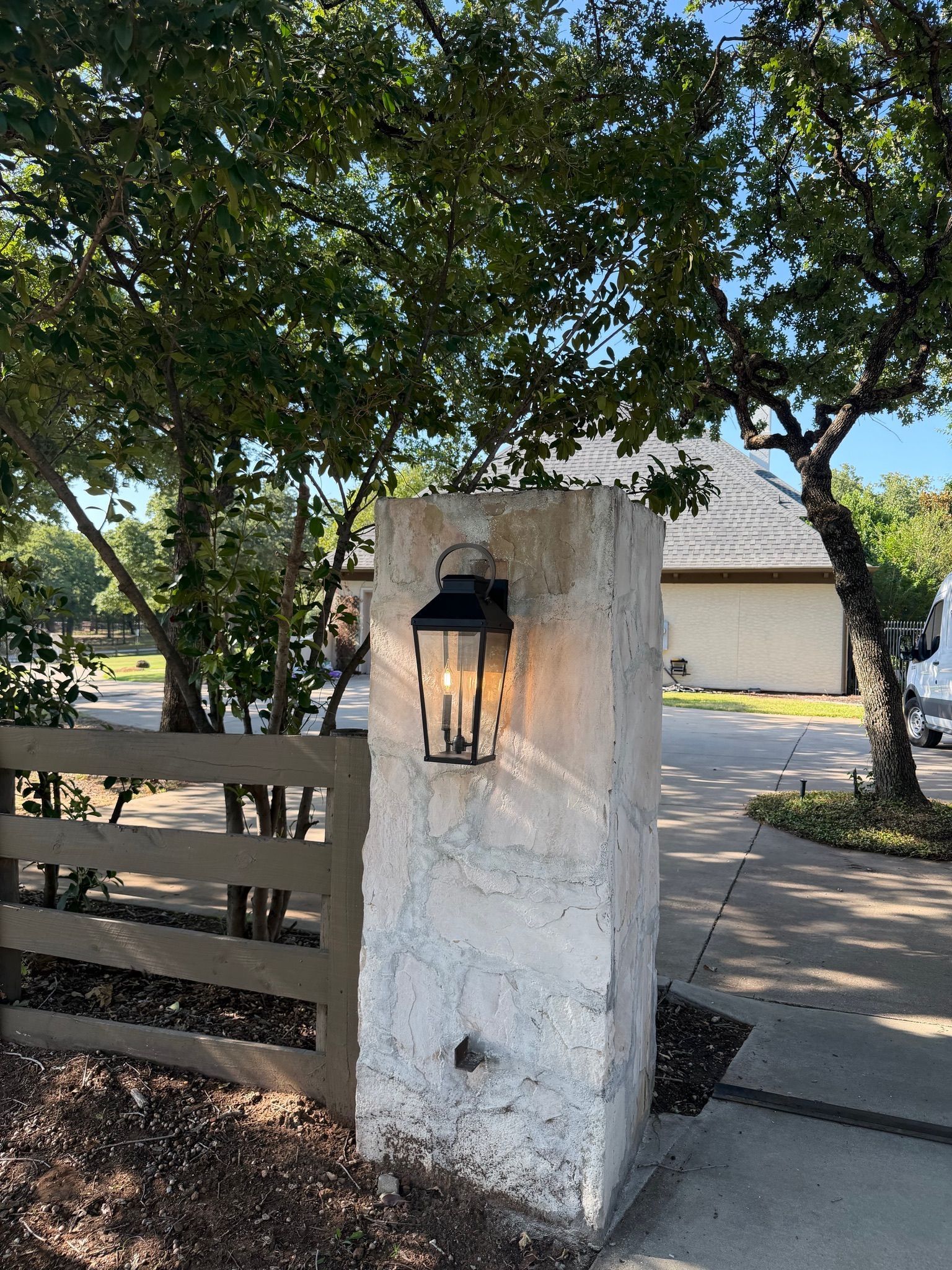Illuminated outdoor coach light installed on a stone entry column by Tier-One Electric.