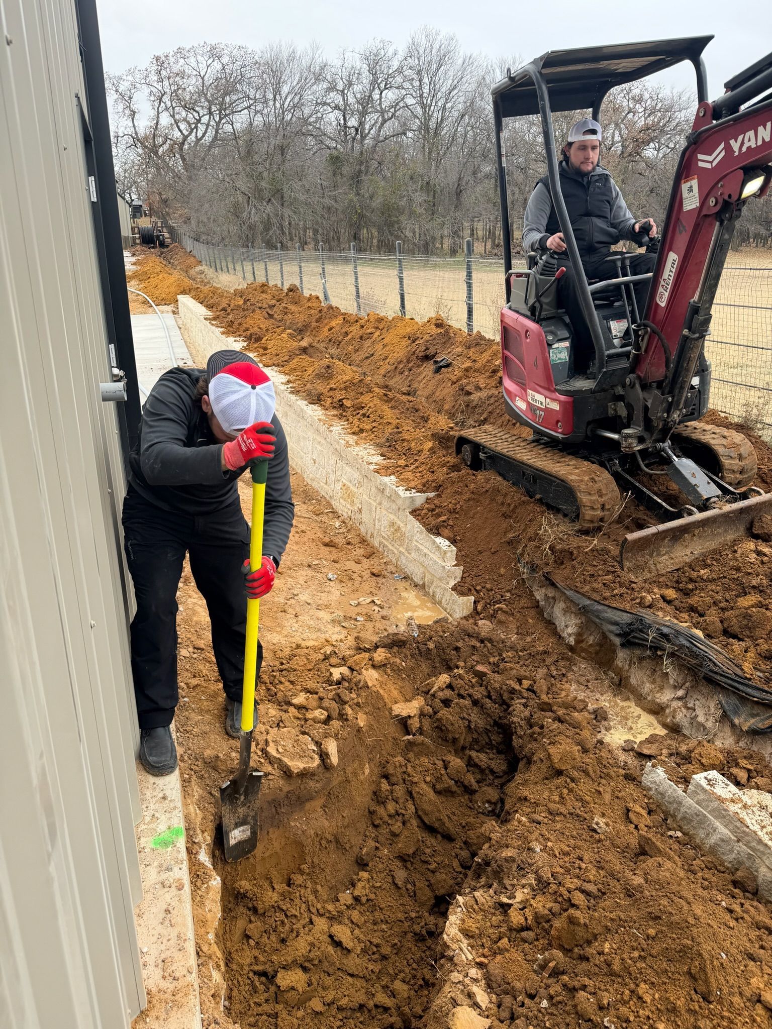 Tier-One Electric technicians digging a trench for underground electrical conduit installation.