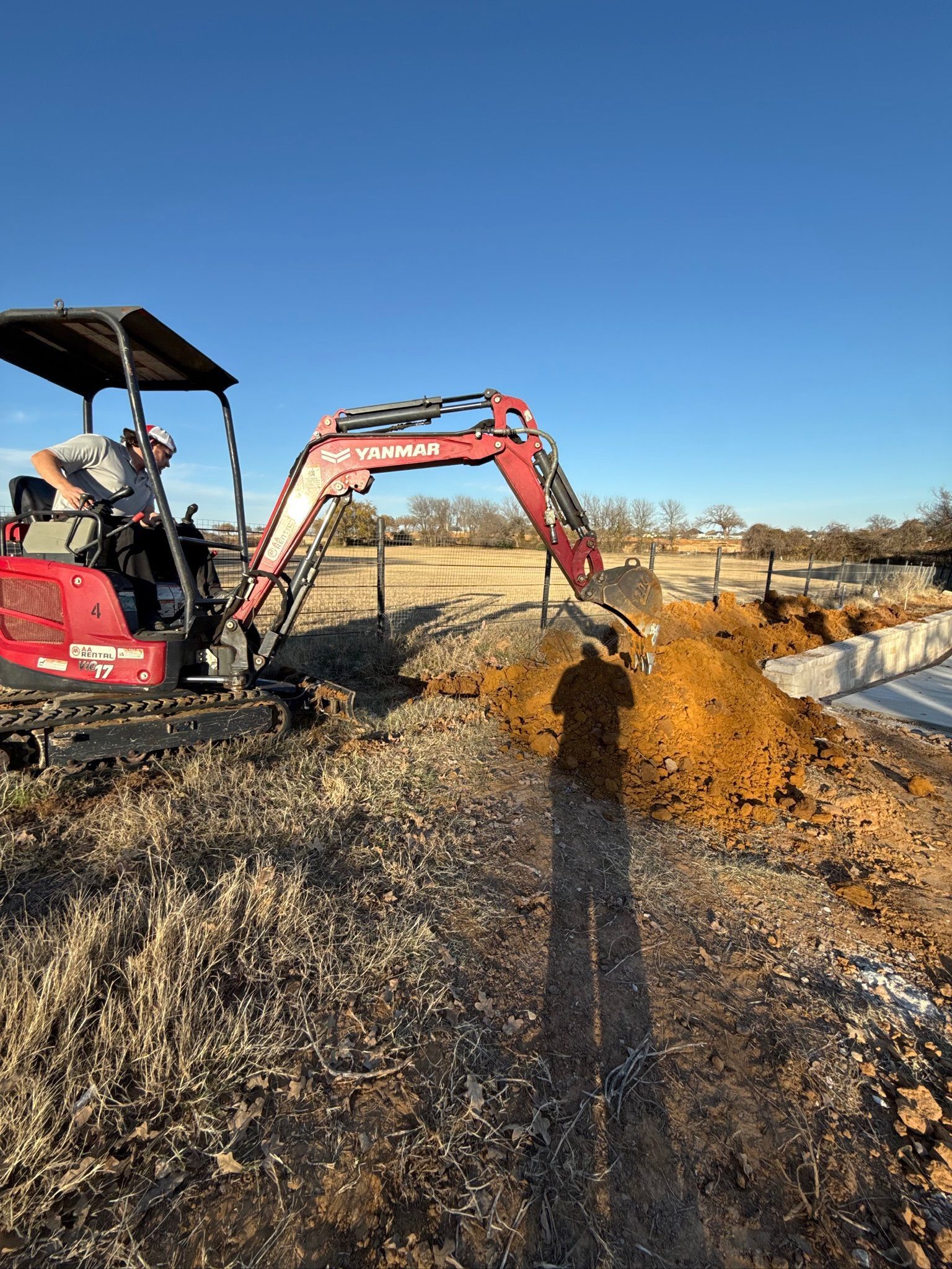 Tier-One Electric technician using an excavator to dig a trench for underground electrical conduit in Bartonville, TX.