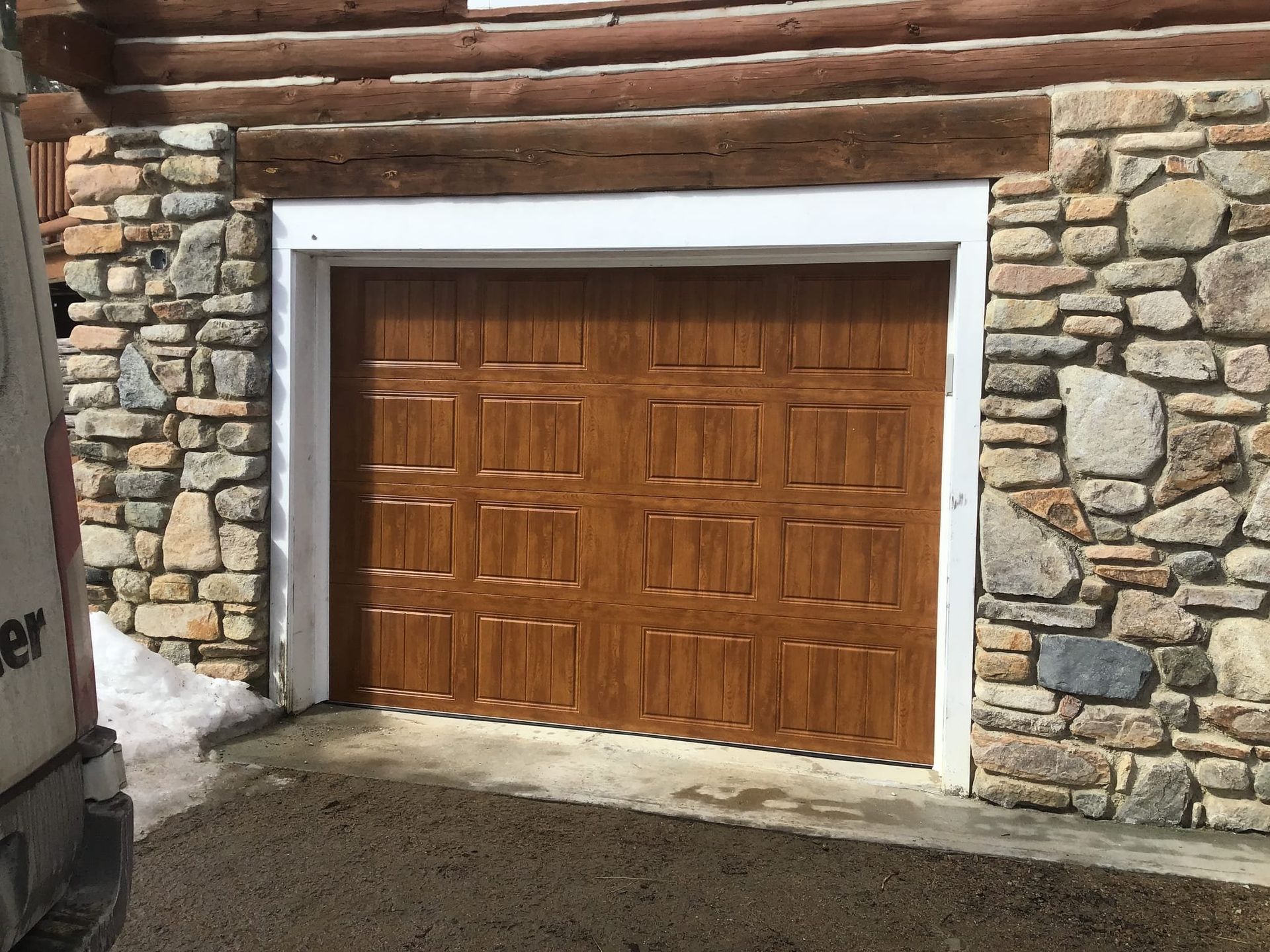 A wooden garage door is sitting in front of a stone wall.