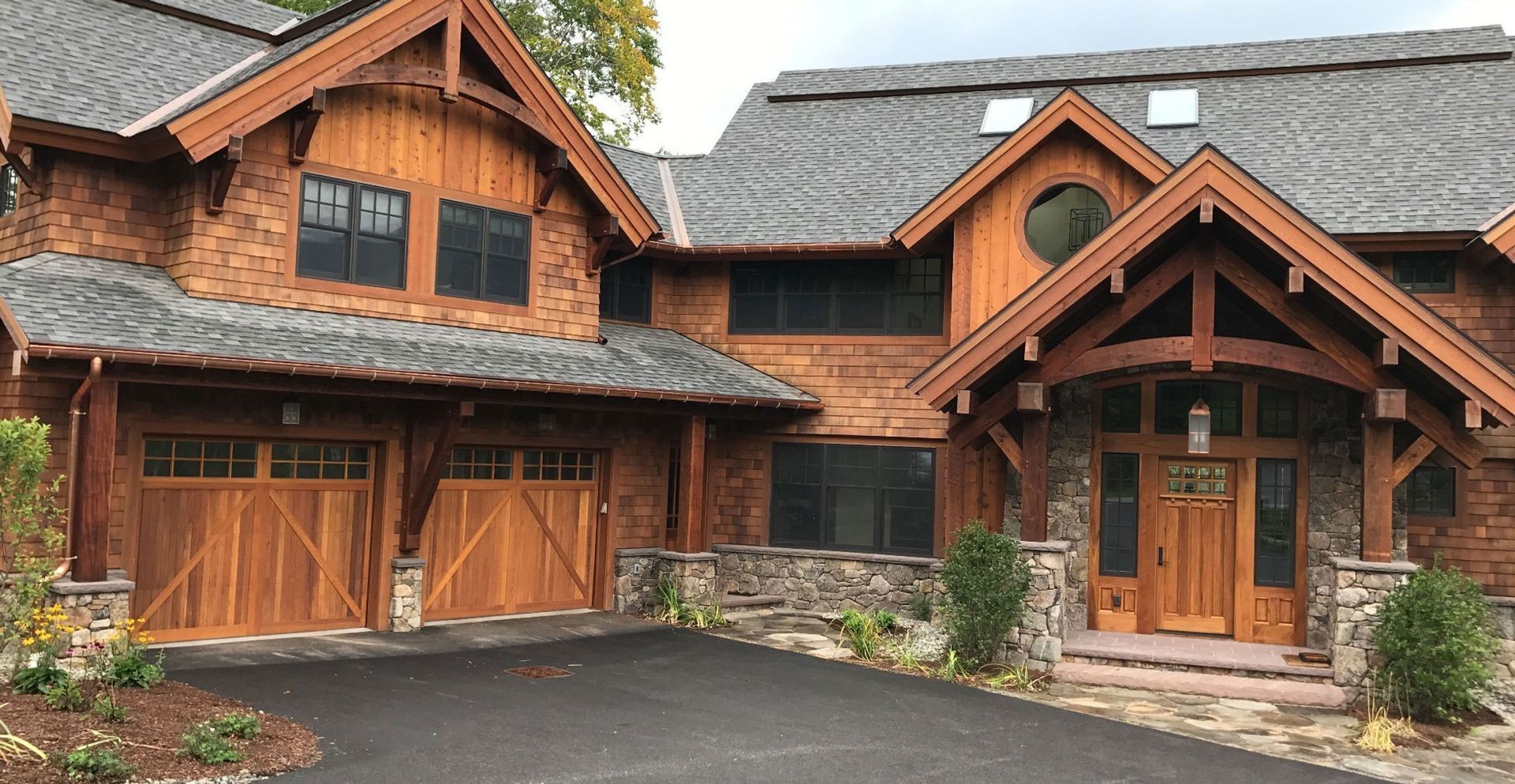 A large wooden house with a driveway in front of it