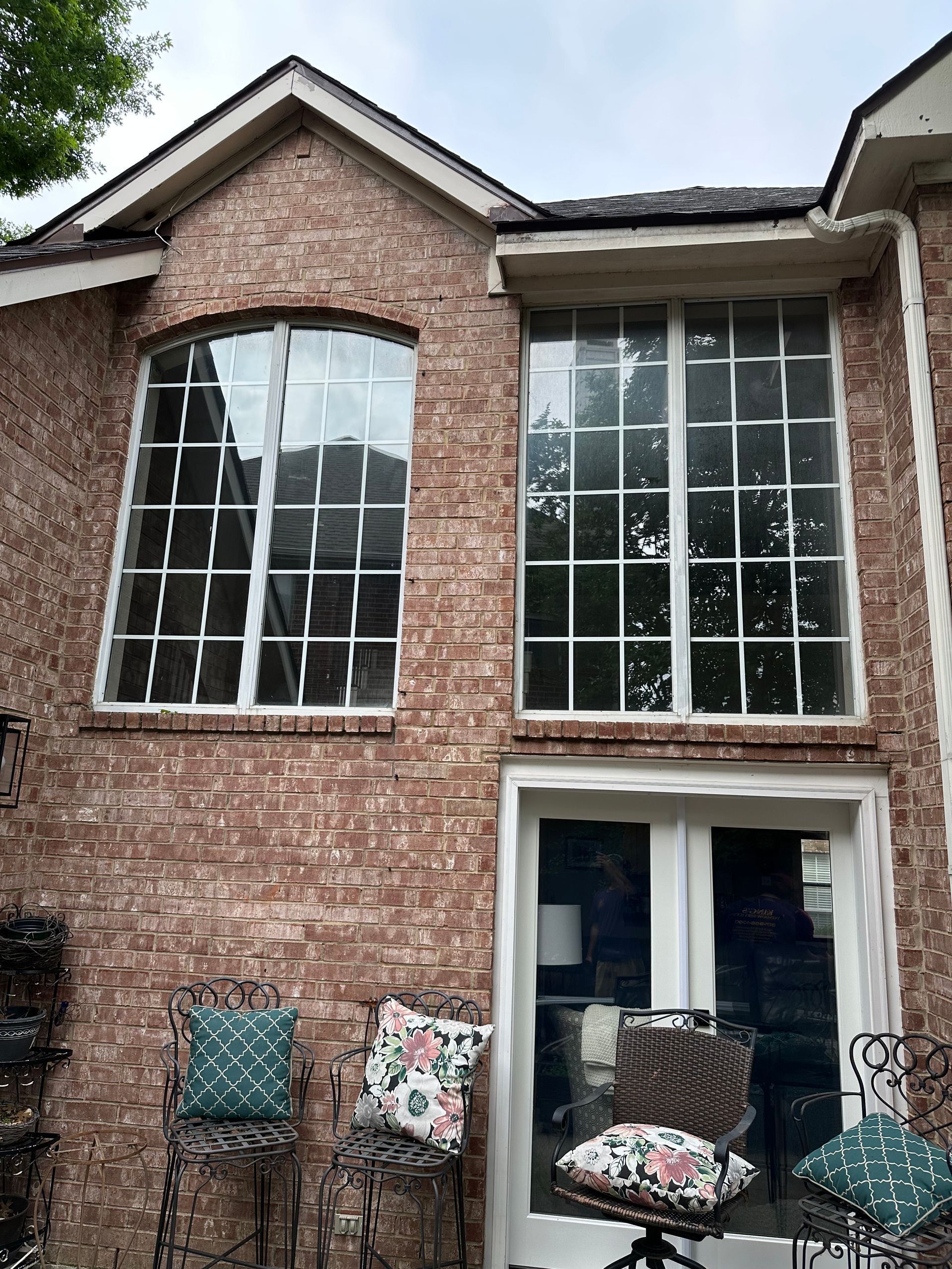 A brick house with a large window and a sliding glass door.
