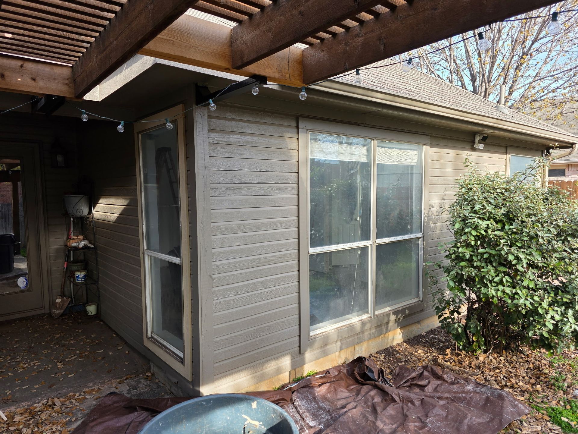 A small house with a lot of windows and a pergola.