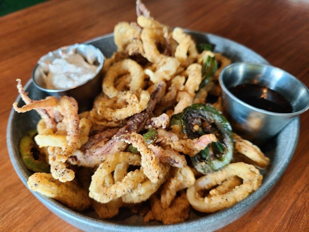A salad with steak and onion rings on a red plate.