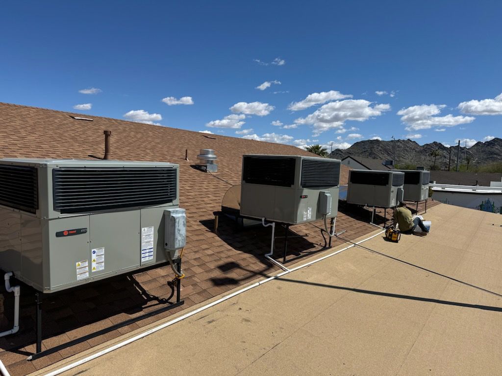 A row of air conditioners are lined up on the roof of a building.