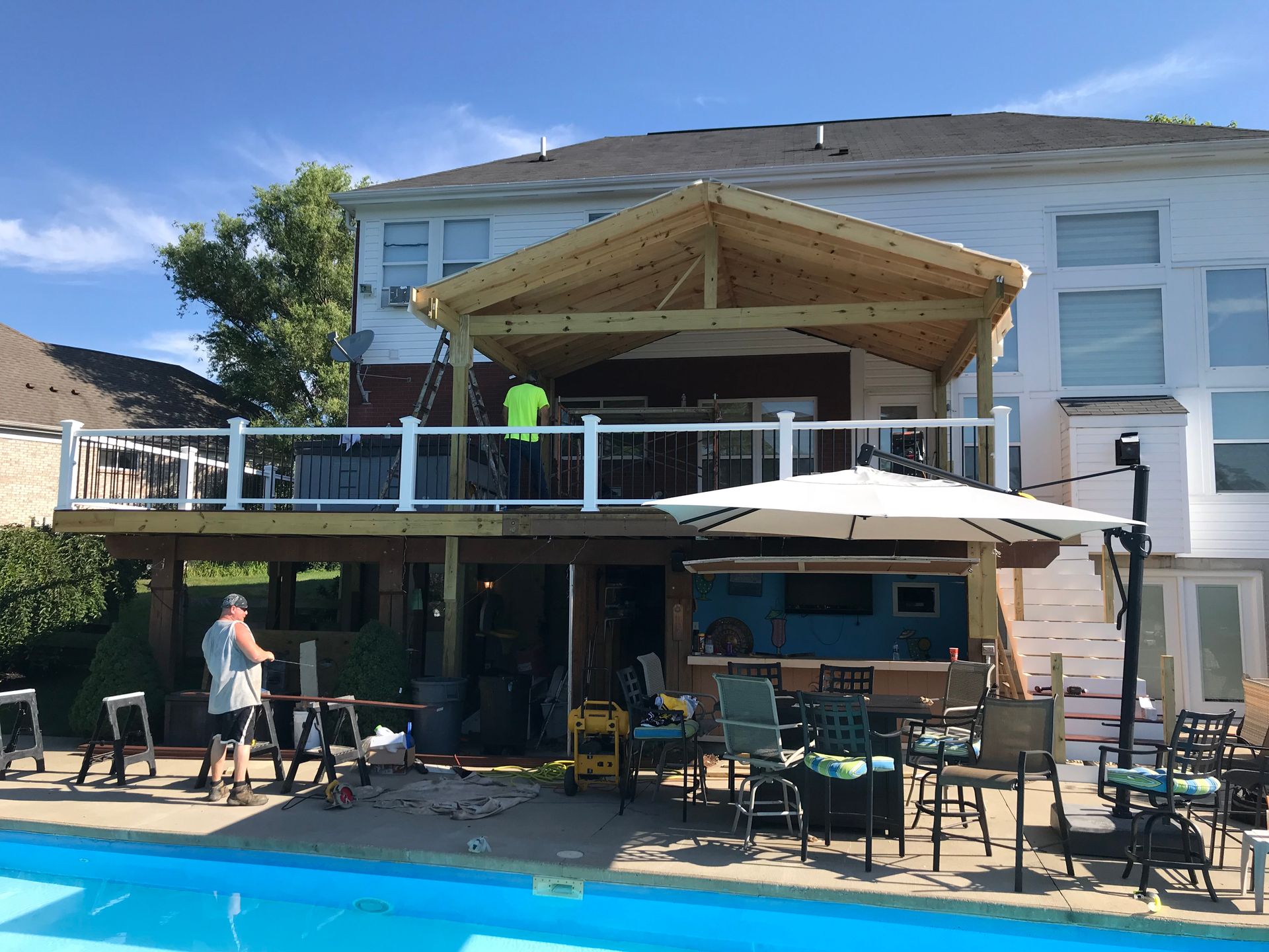 Outdoor restaurant patio with white umbrellas and a shaded deck beside a modern building