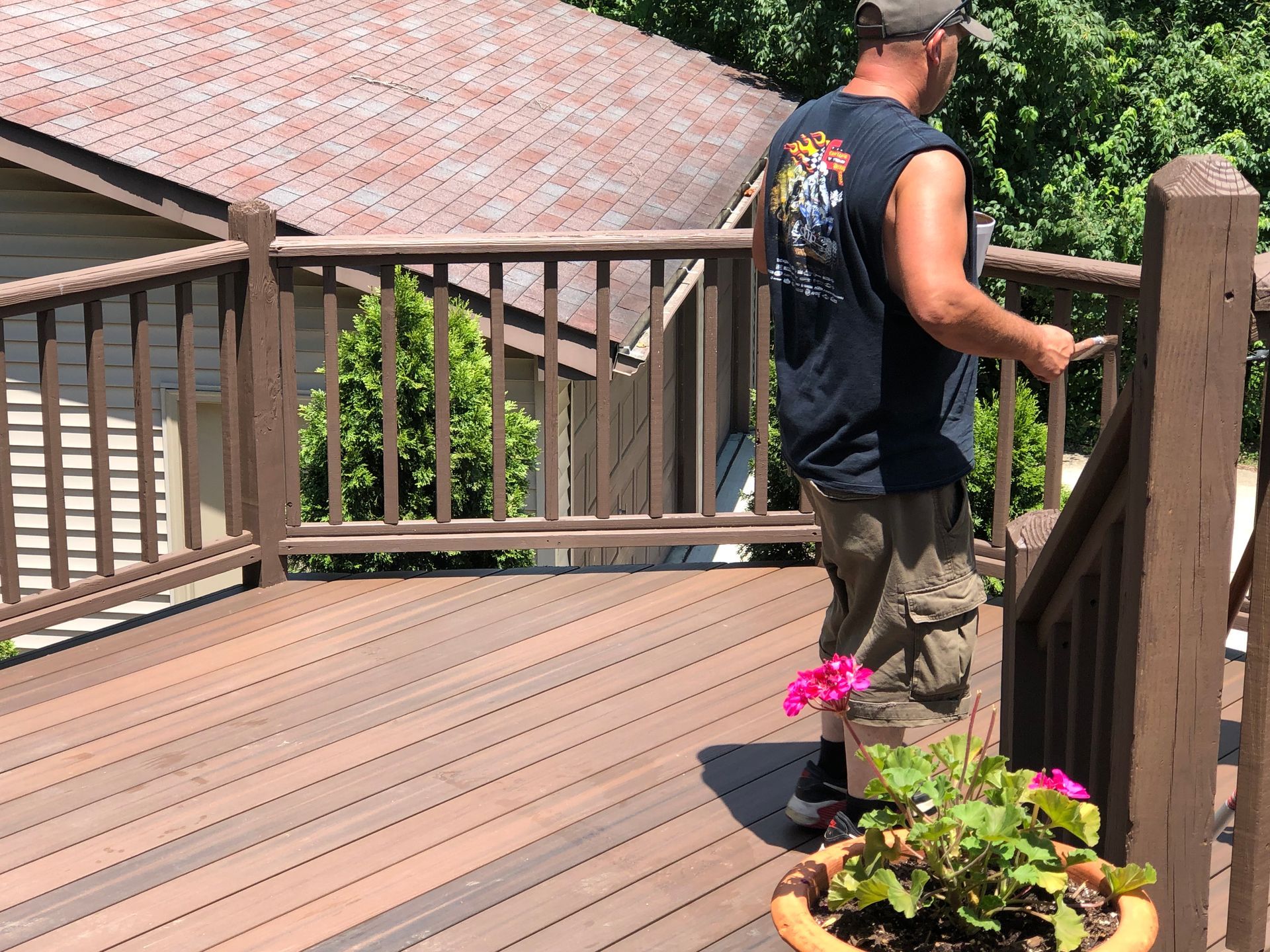 Person standing on a wooden deck overlooking a tiled roof and greenery