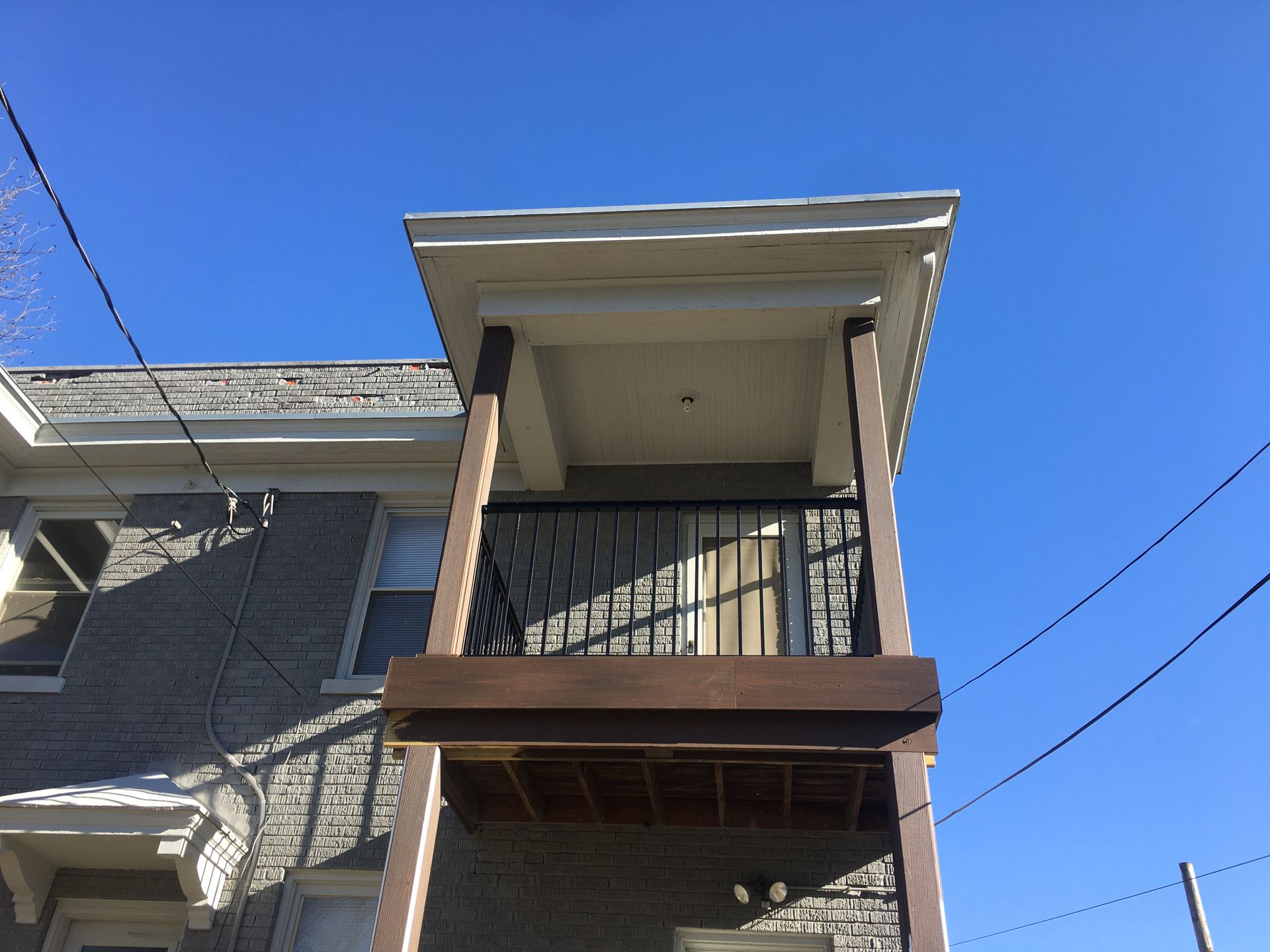 Two-story brick building balcony with white trim under a clear blue sky