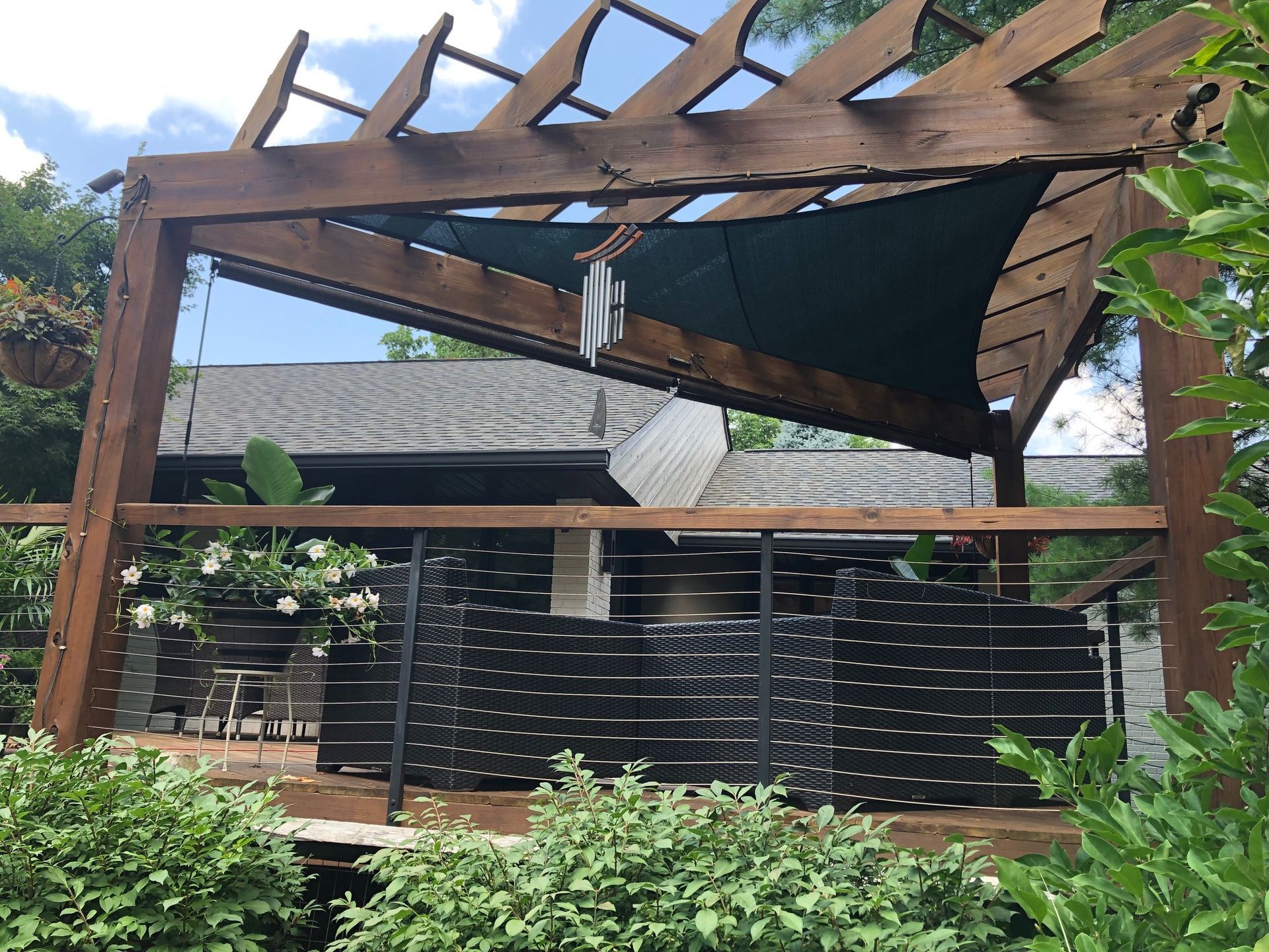 Outdoor patio with a partially collapsed wooden pergola over a seating area and black fence.