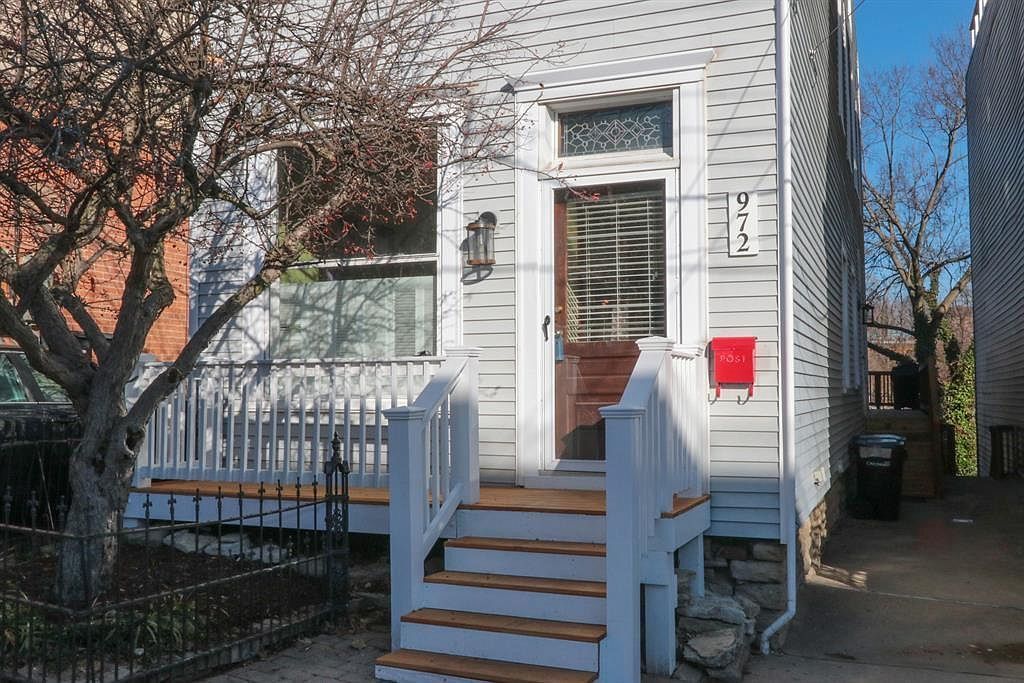 White house entrance with steps, railing, and a red mailbox on the front porch.