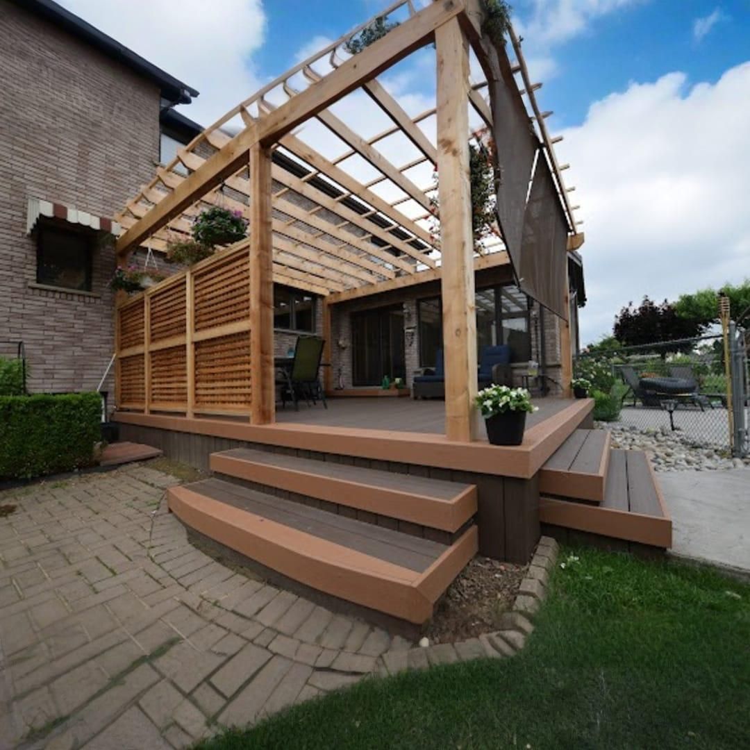A wooden pergola with a privacy screen stands over a multi-level deck with steps leading down to a brick patio.