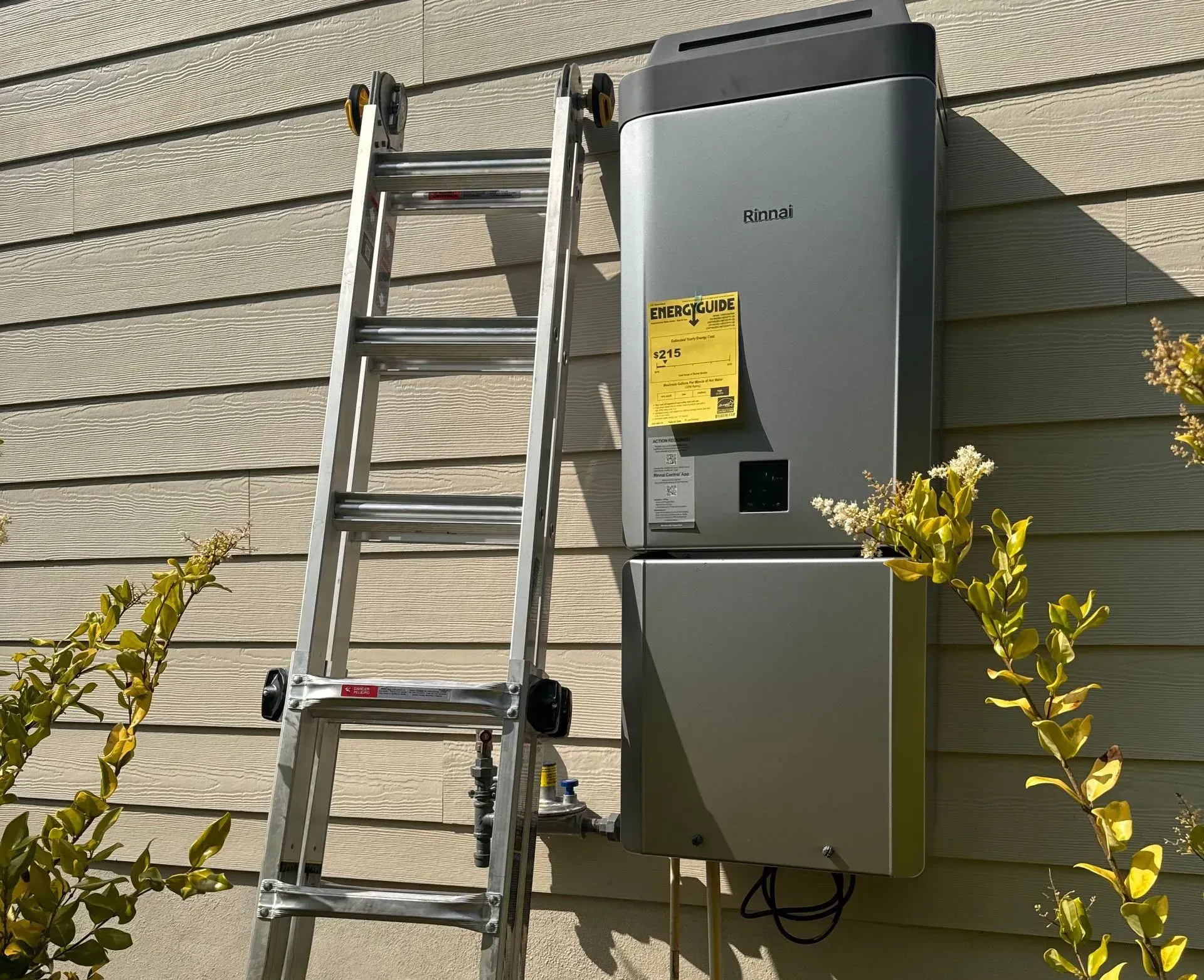 Ladder leaning against a house with a gray electrical unit installed on the siding.