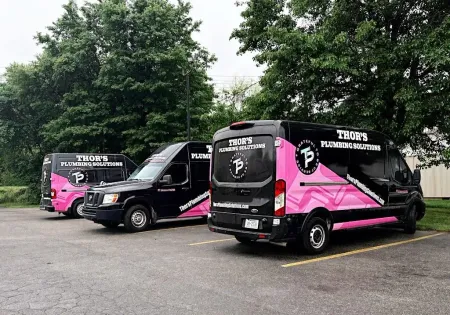 Three black vans with pink graphics parked outside.