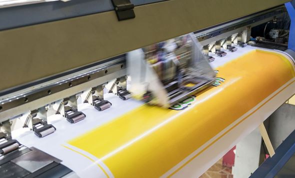Large-format printer printing a yellow and white graphic.