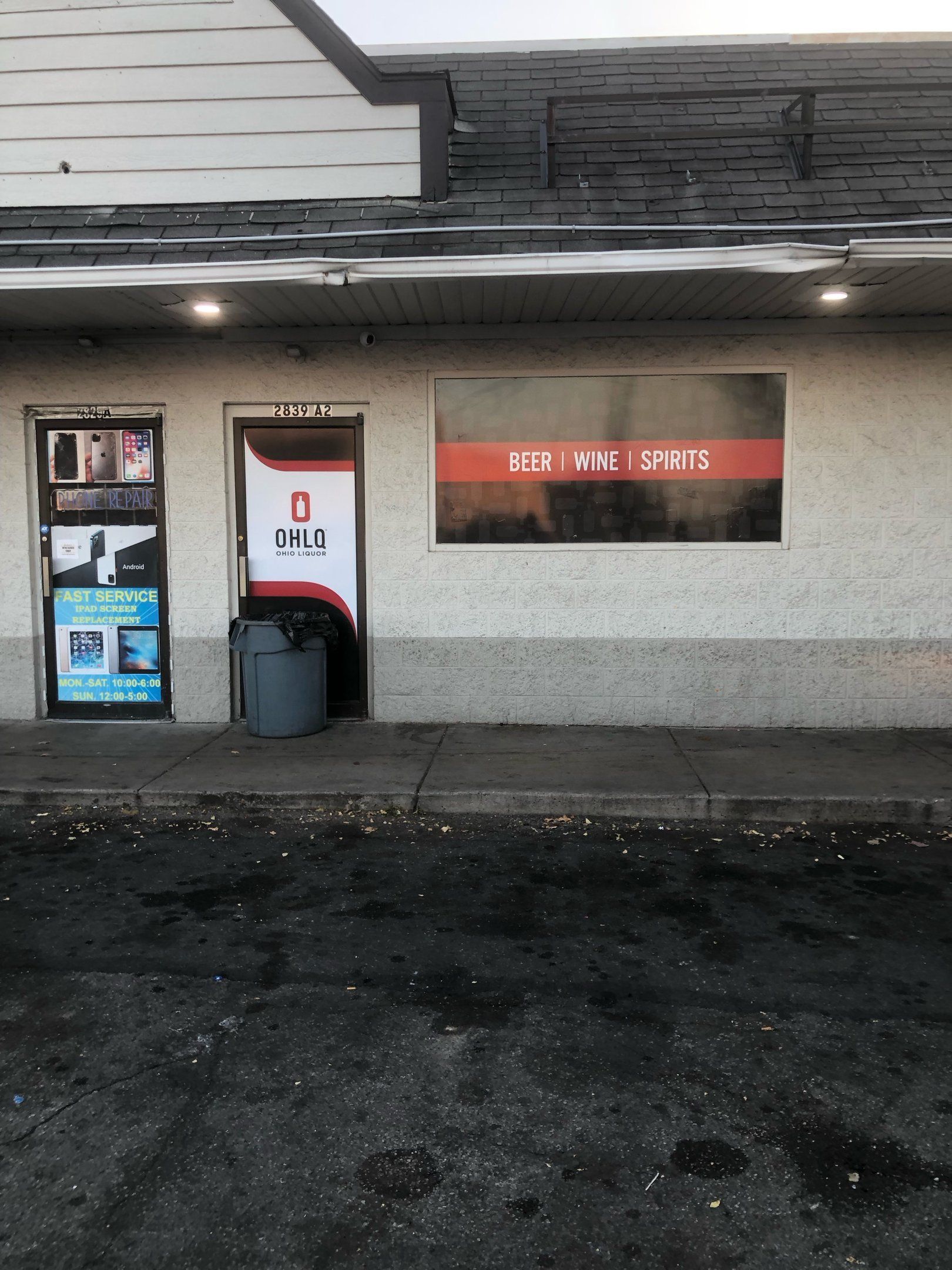 Exterior of a small, weathered business with a door and a large window with red text.
