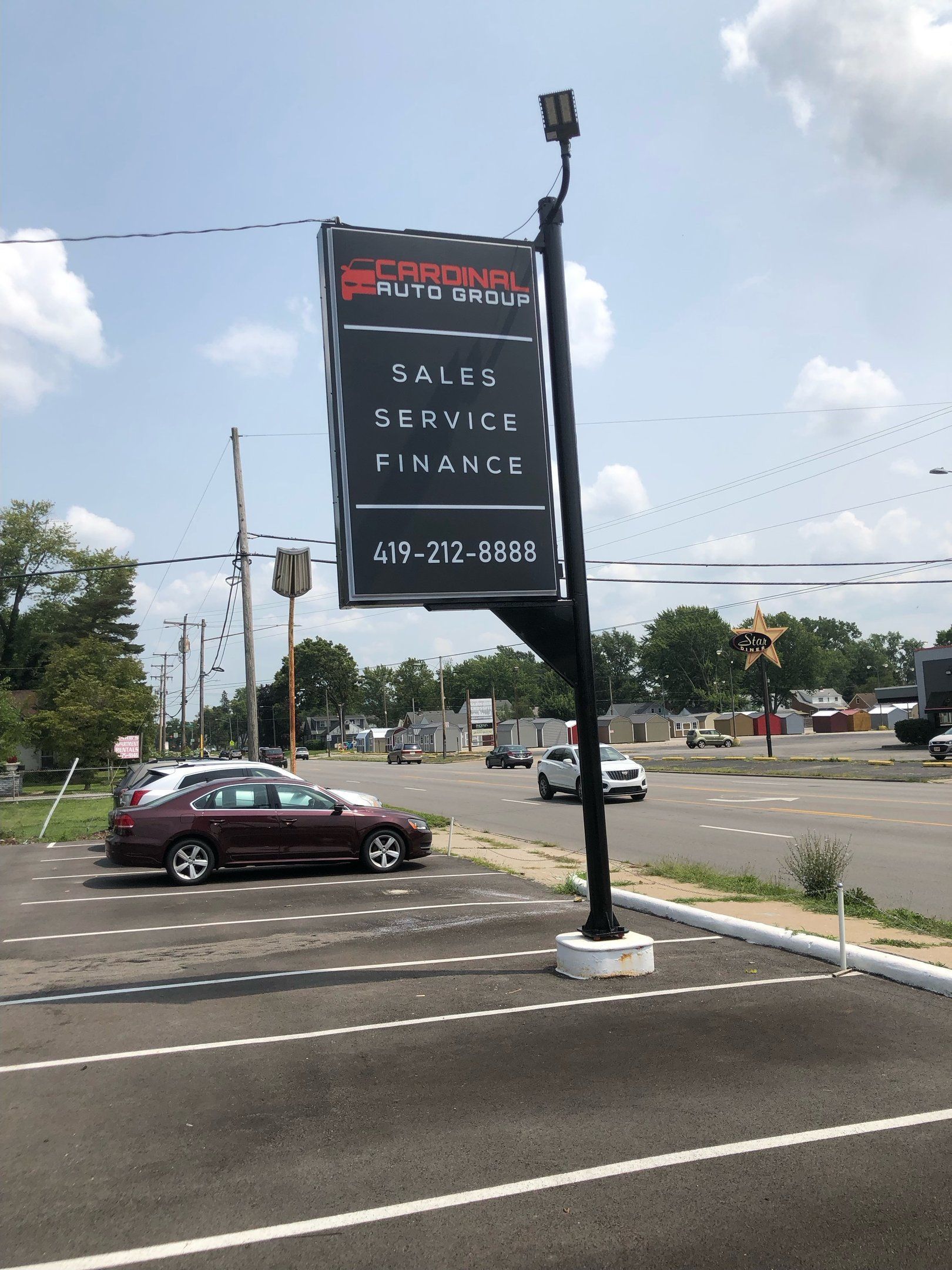 Sign for auto dealership on a black pole, displaying 