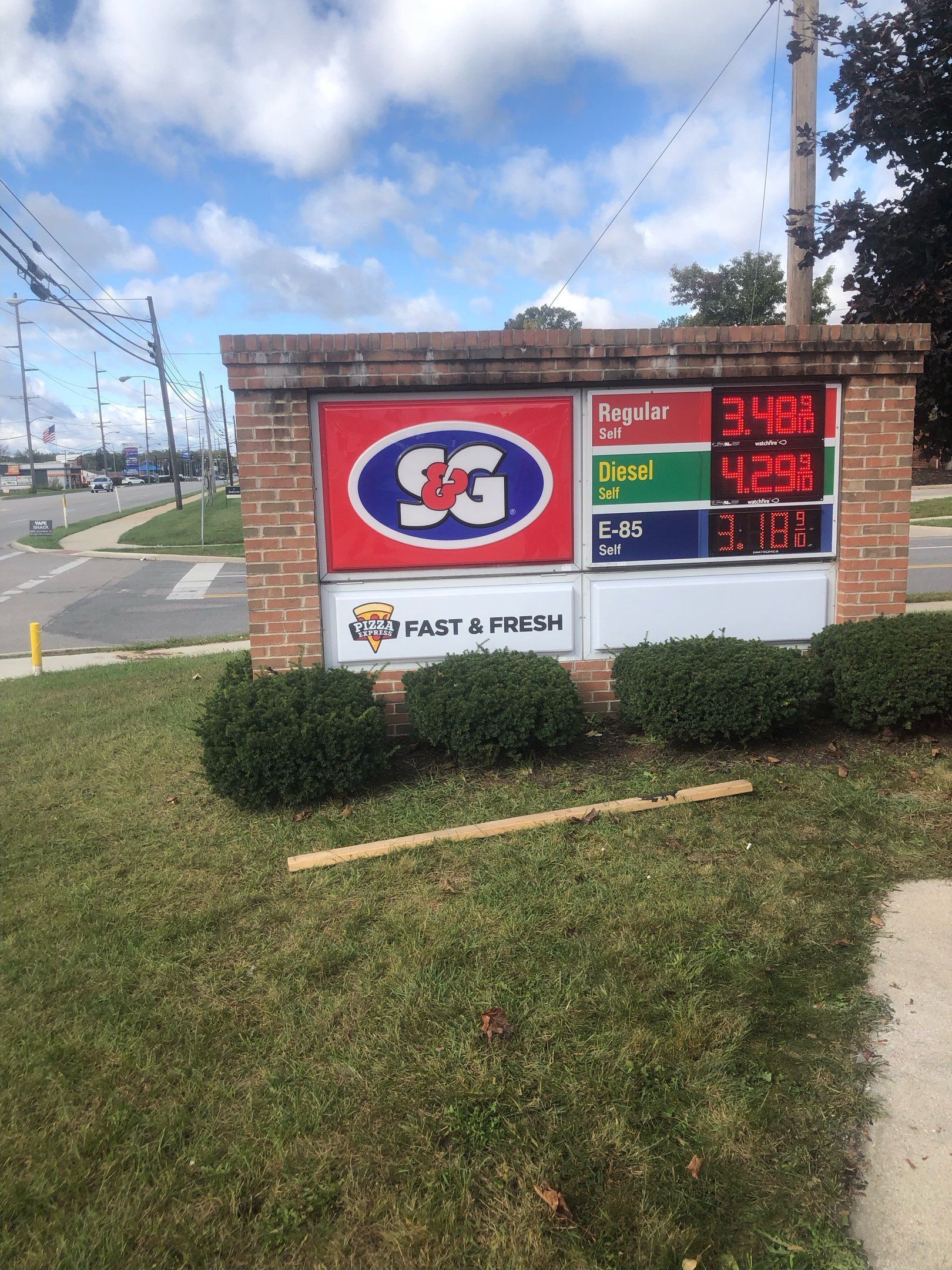 Gas station sign with red, blue, and green price displays; brick base; logo 